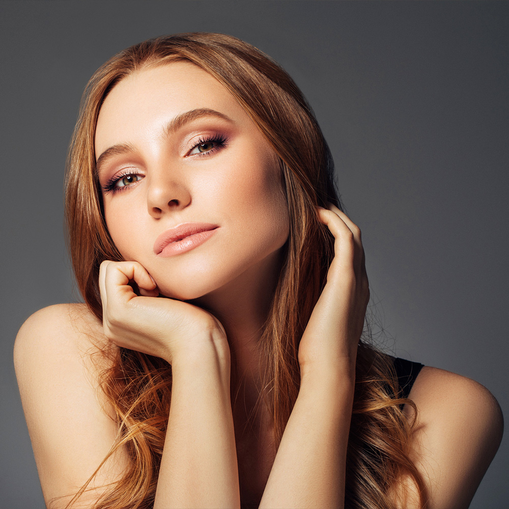 Young redhead holds hands to her face and shows off glowing skin from PRF.